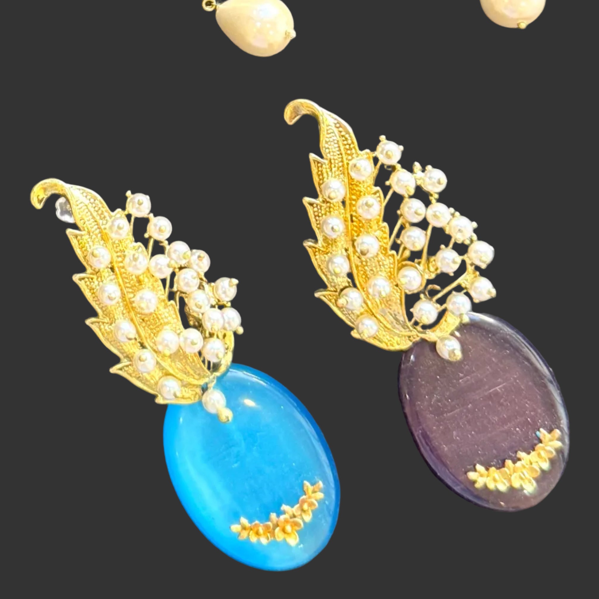 A collection of ornate gold-toned jewelry pieces, including earrings and a leaf shaped piece